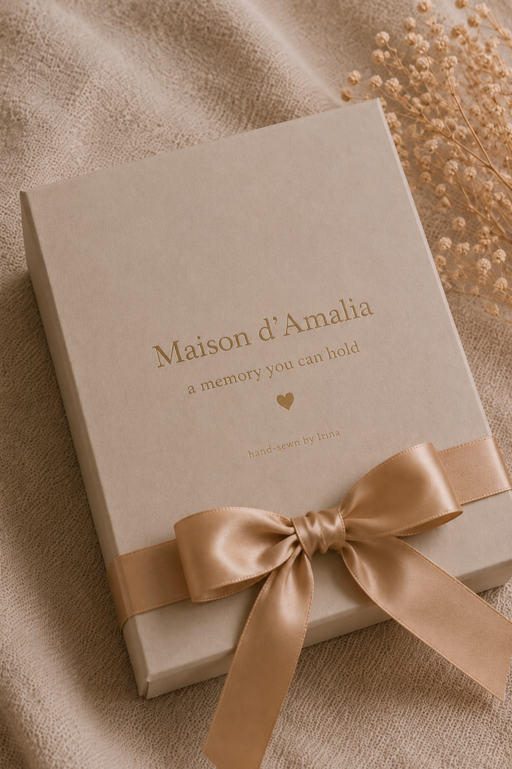 Maison d'Amalia keepsake box tied with a gold satin bow, reading 'a memory you can hold, hand-sewn by Irina'